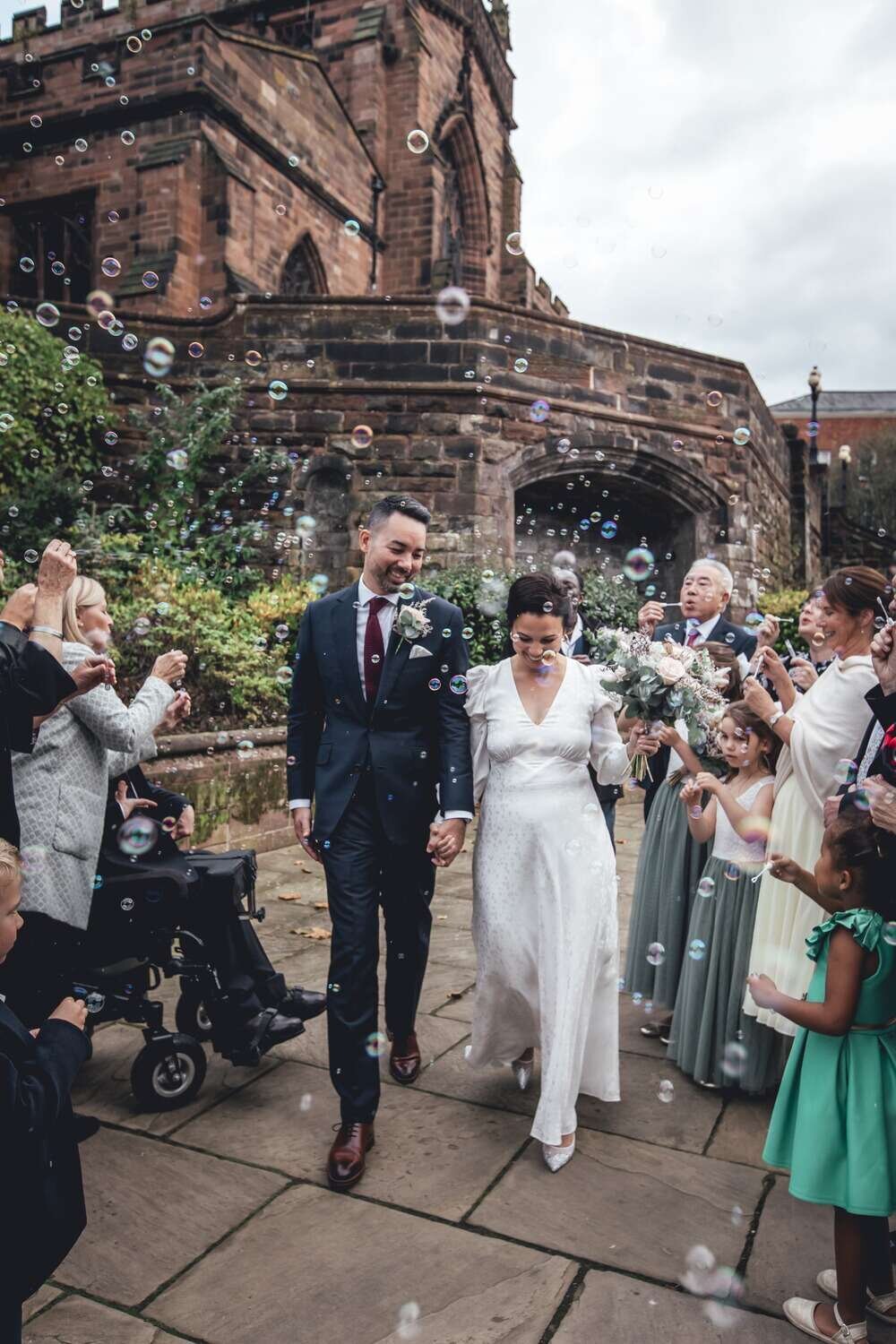 Bride and Groom walk through tunner of friends and family blowing bubbles in the air