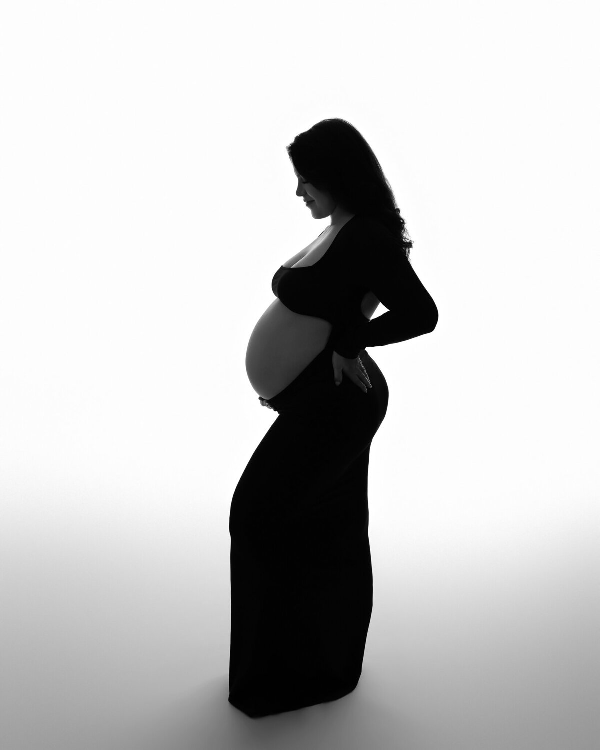 Studio maternity silhouette in long black gown with soft lighting near Westlake, Texas