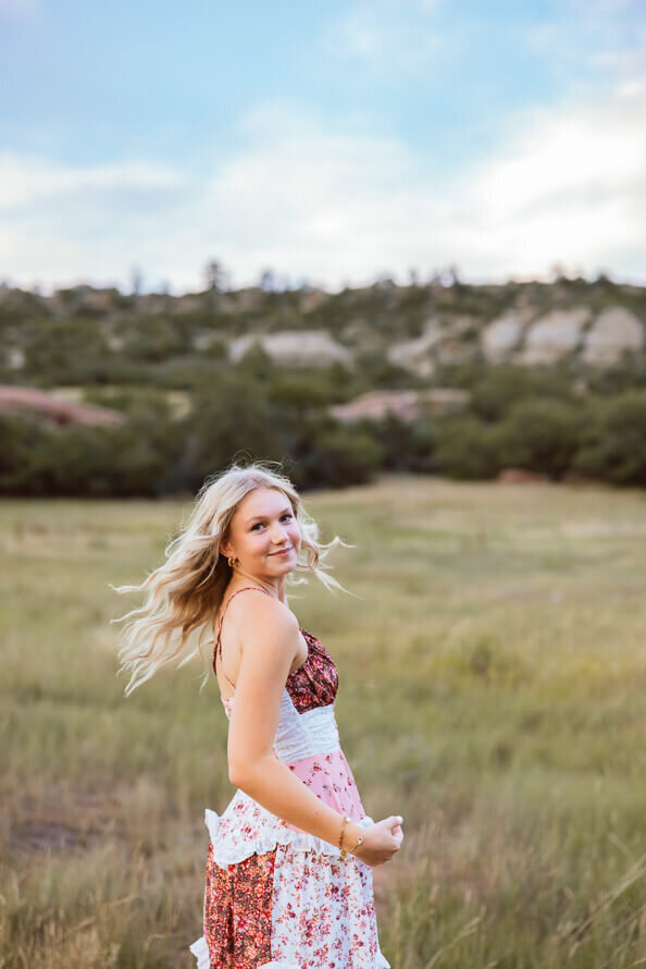 Girl flips hair and dances in a grassy field.