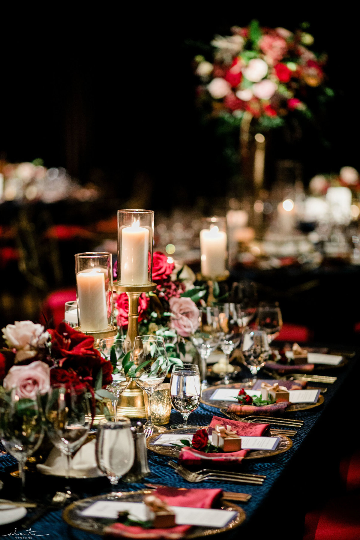 long wedding reception table lined with candles and red flowers
