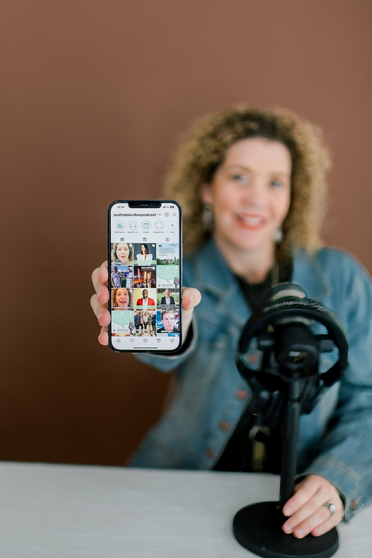 podcaster for Scottsdale vibes podcast at a studio holding up her social media grid for brand portrait
