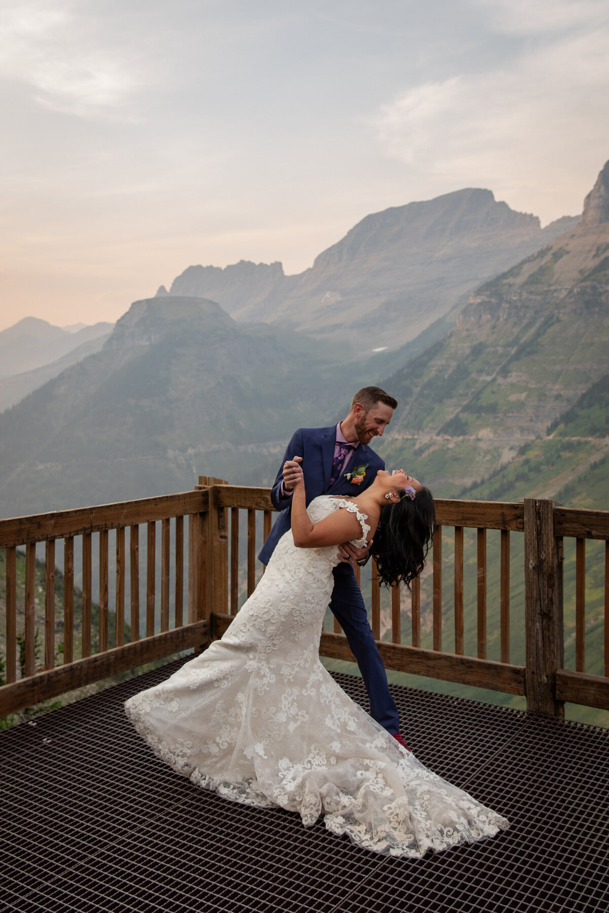 A groom dips his bride as she laughs.
