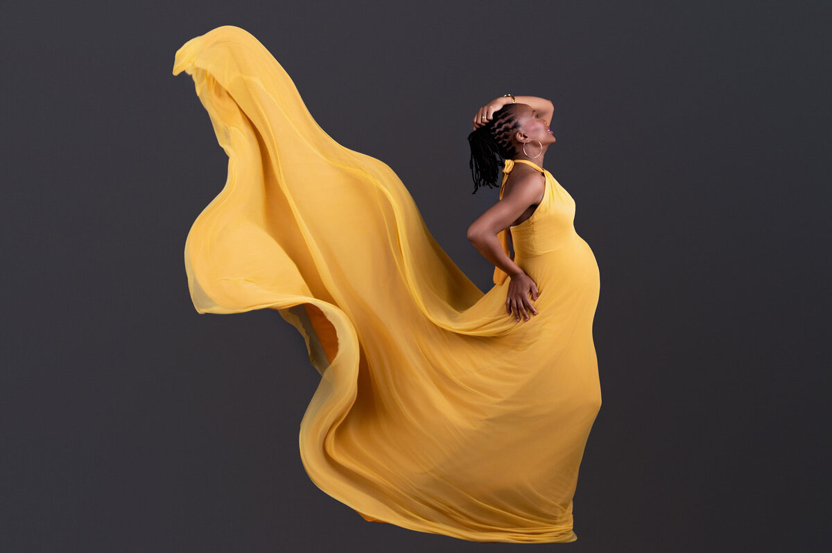 Mom-to-be posing in elegant mustard yellow maternity gown.