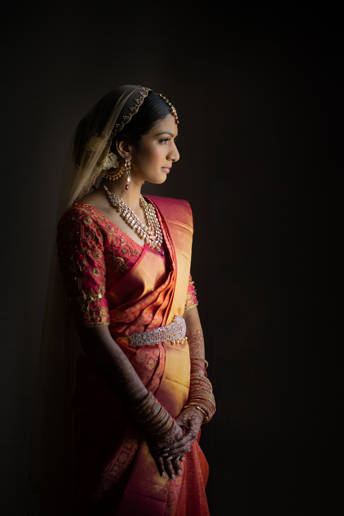 A bride in traditional Indian clothes looking off to the side.