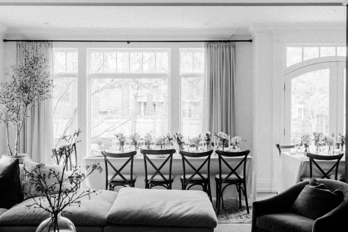 A classic black-and-white photograph of an elegantly set dining room with floral arrangements, creating a sophisticated ambiance