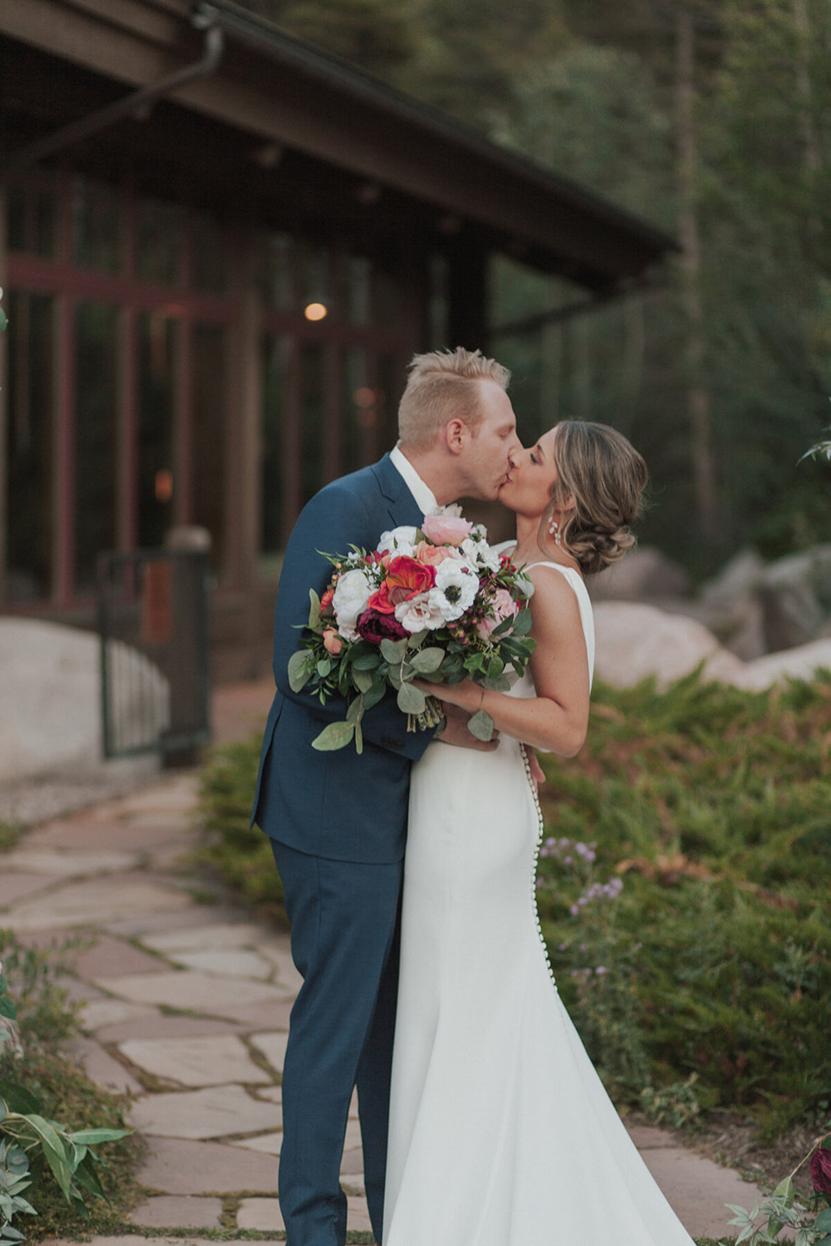 Alana and Ryan kissing each other on their wedding day while Alana holding her floral bouquet