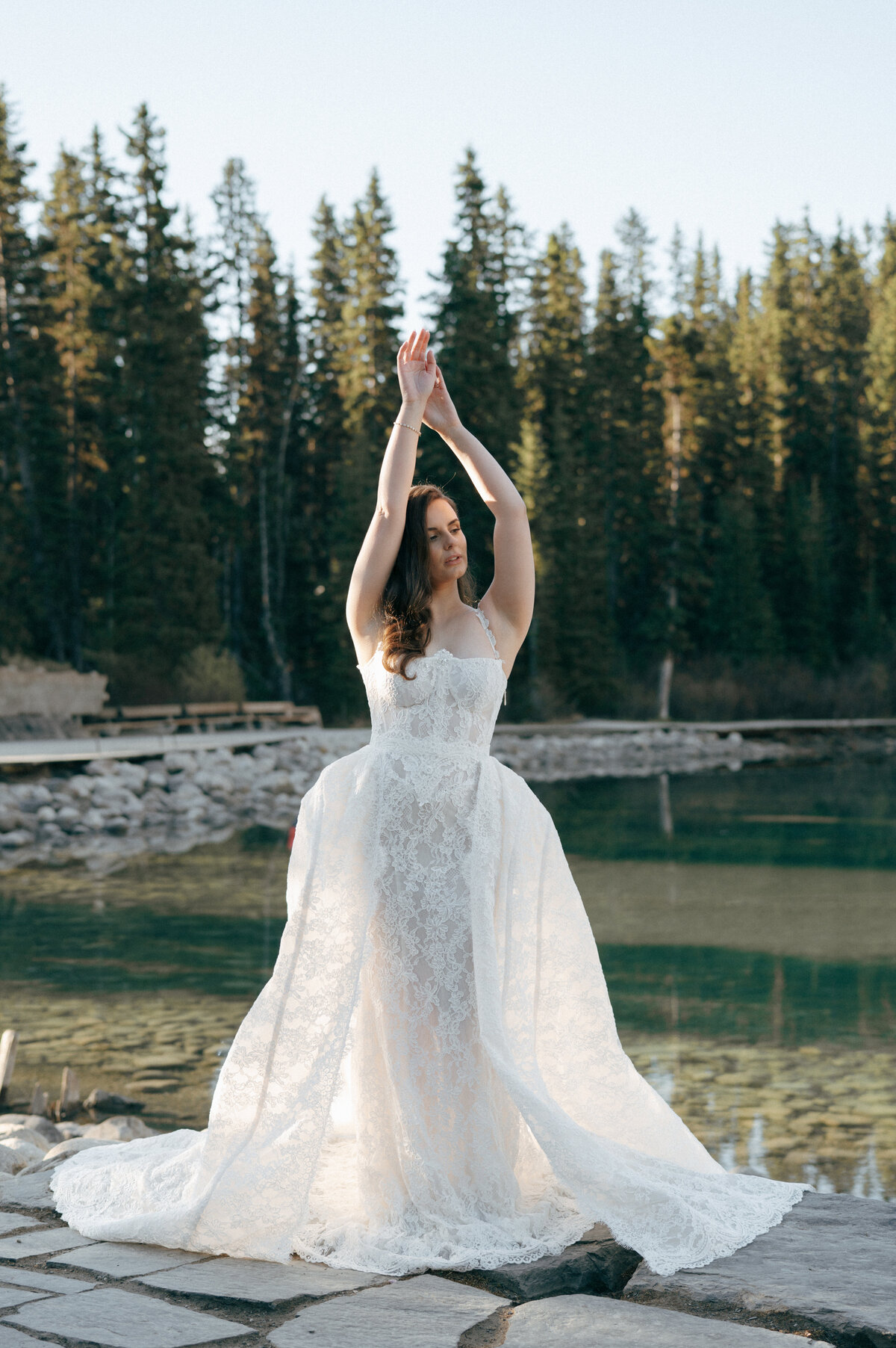 Bride posing at golden hour in pine forest at Lake Louise