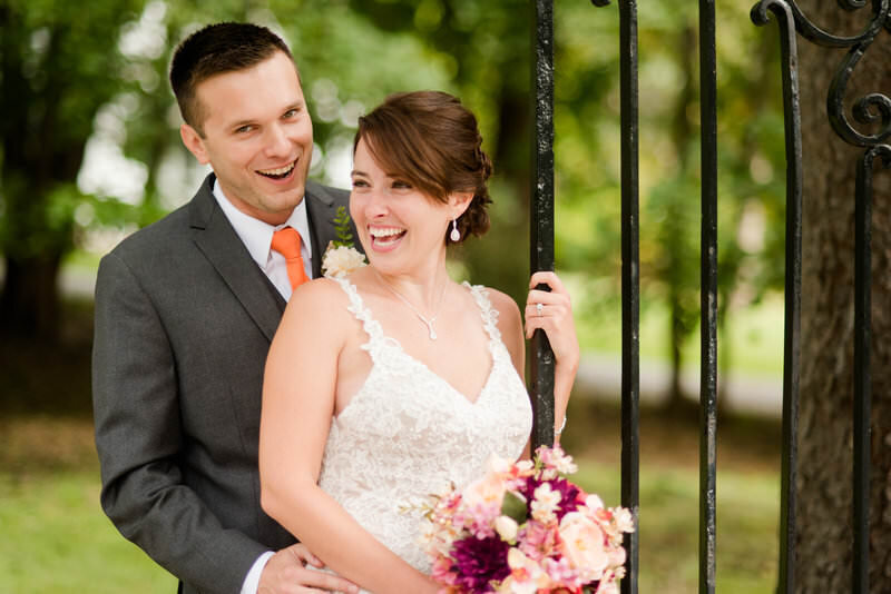 wedding couple smiling for photos with an iron gate at their coraopolis pennsylvania wedding
