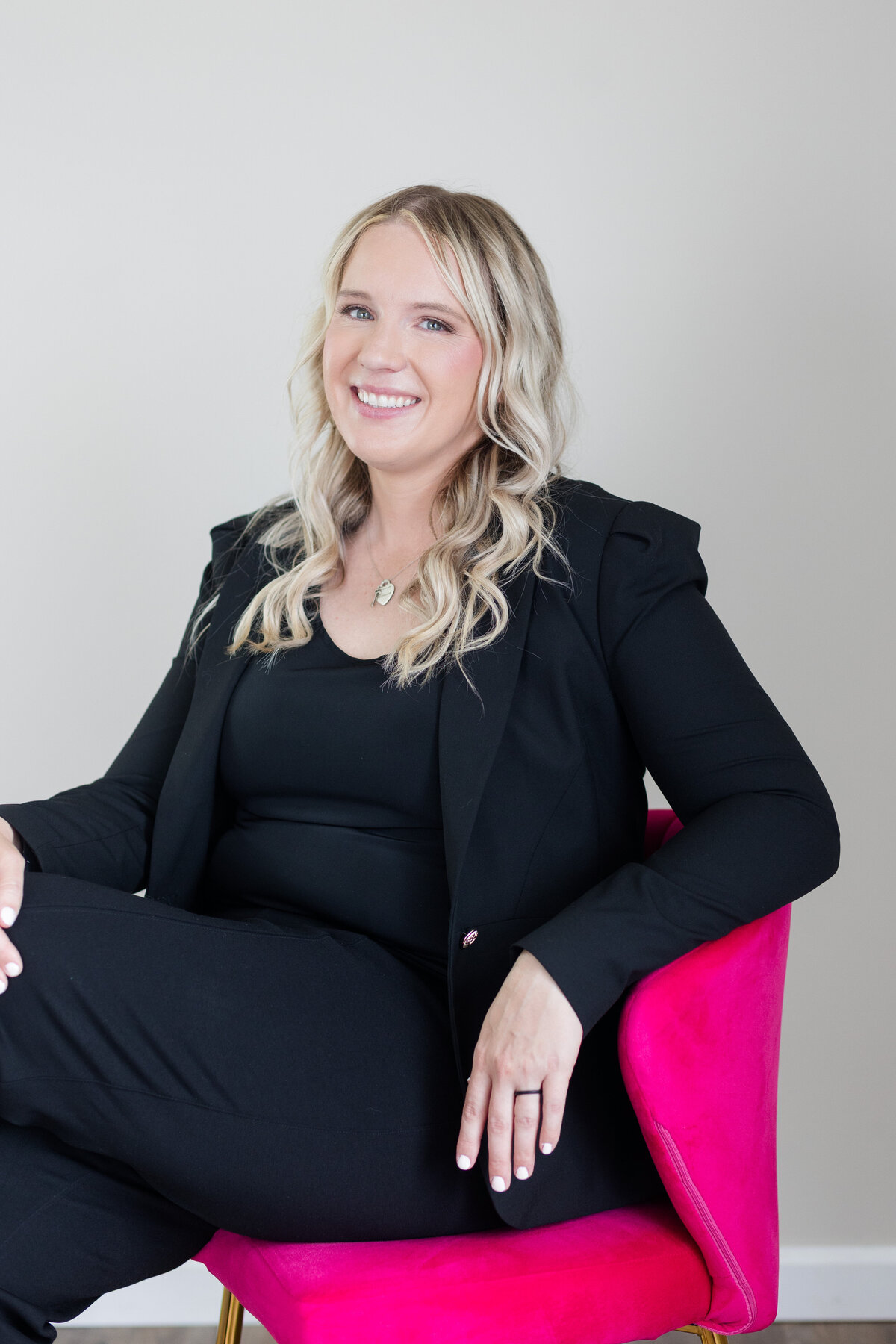 Jessica wearing a white blazer, smiling as she writes in her planner