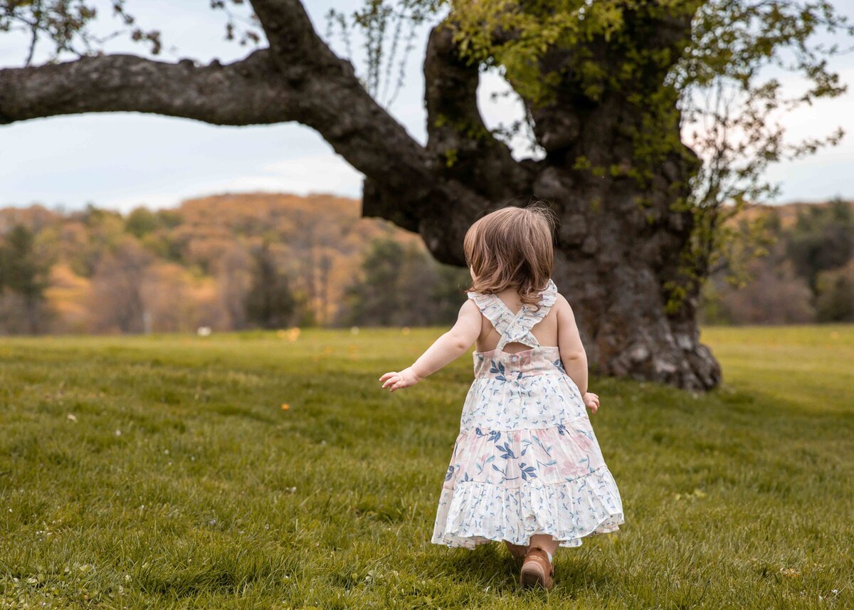 baby girl runs through a field at Topsmead in Litchfield Connecticut