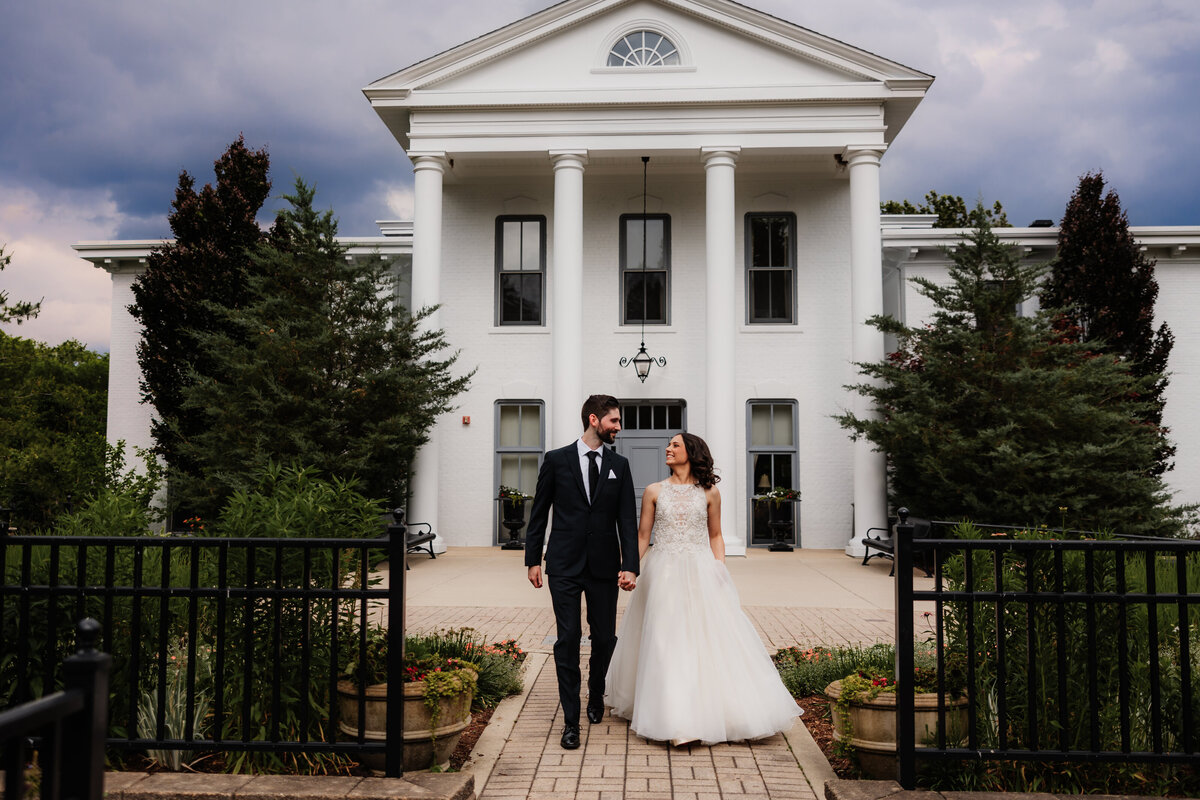 A bride and groom walk together at the Wilder Mansion.