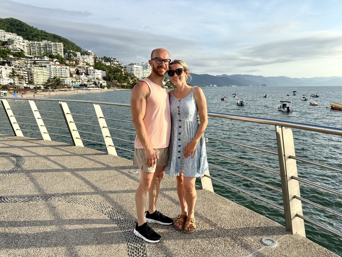 Minnesota wedding photographer with his wife at Los Muertos Beach Pier in Puerto Vallarta, with ocean in the background, captured by Minnesota wedding photographer. 