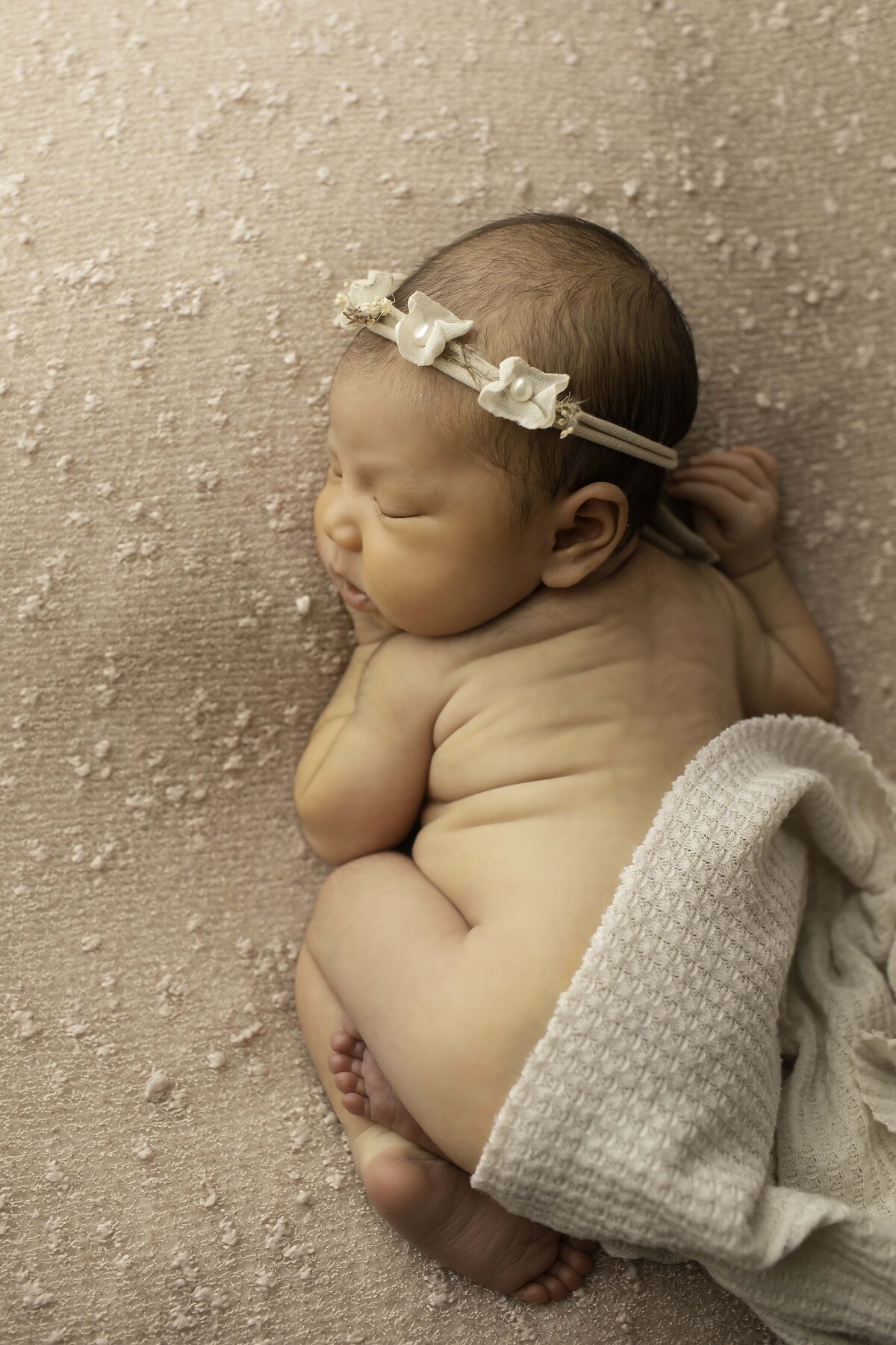 Newborn baby girl peacefully lying on soft fabric, her delicate features and serene expression creating a gentle and timeless portrait