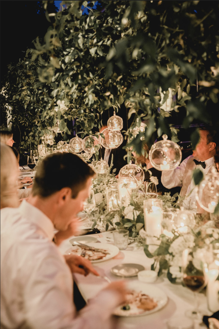 Guests celebrating at an outdoor summer event at Hasbrouck House in Stone Ridge, NY, surrounded by lush greenery and white florals.