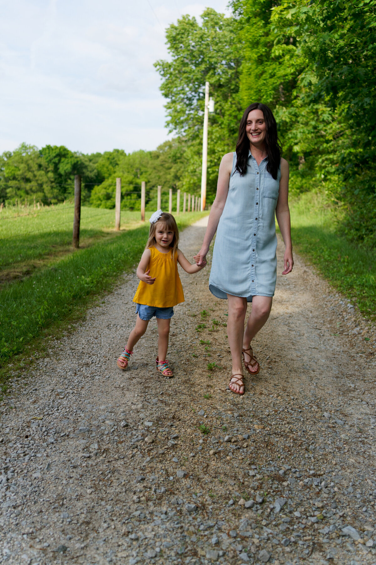 girl and mom walking on gravel road outdoor daytime portrait