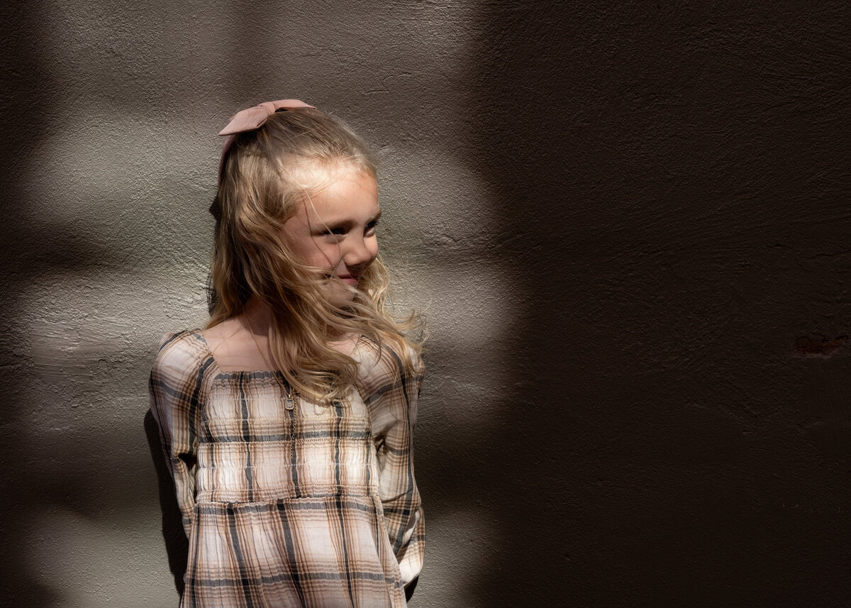 A child stands alone in a dark alley, bathed in a beam of sunlight