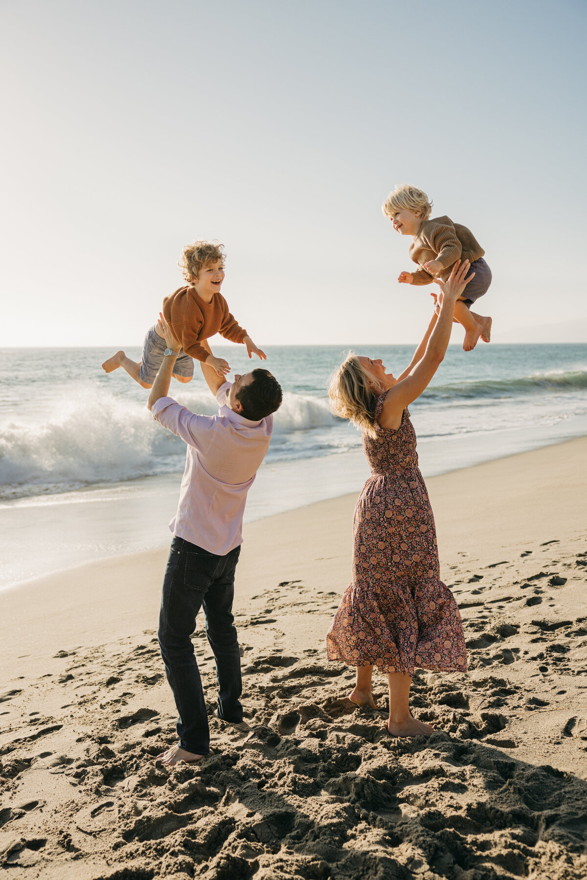 Mom and Dad tossing their laughing kids in the air on the beach