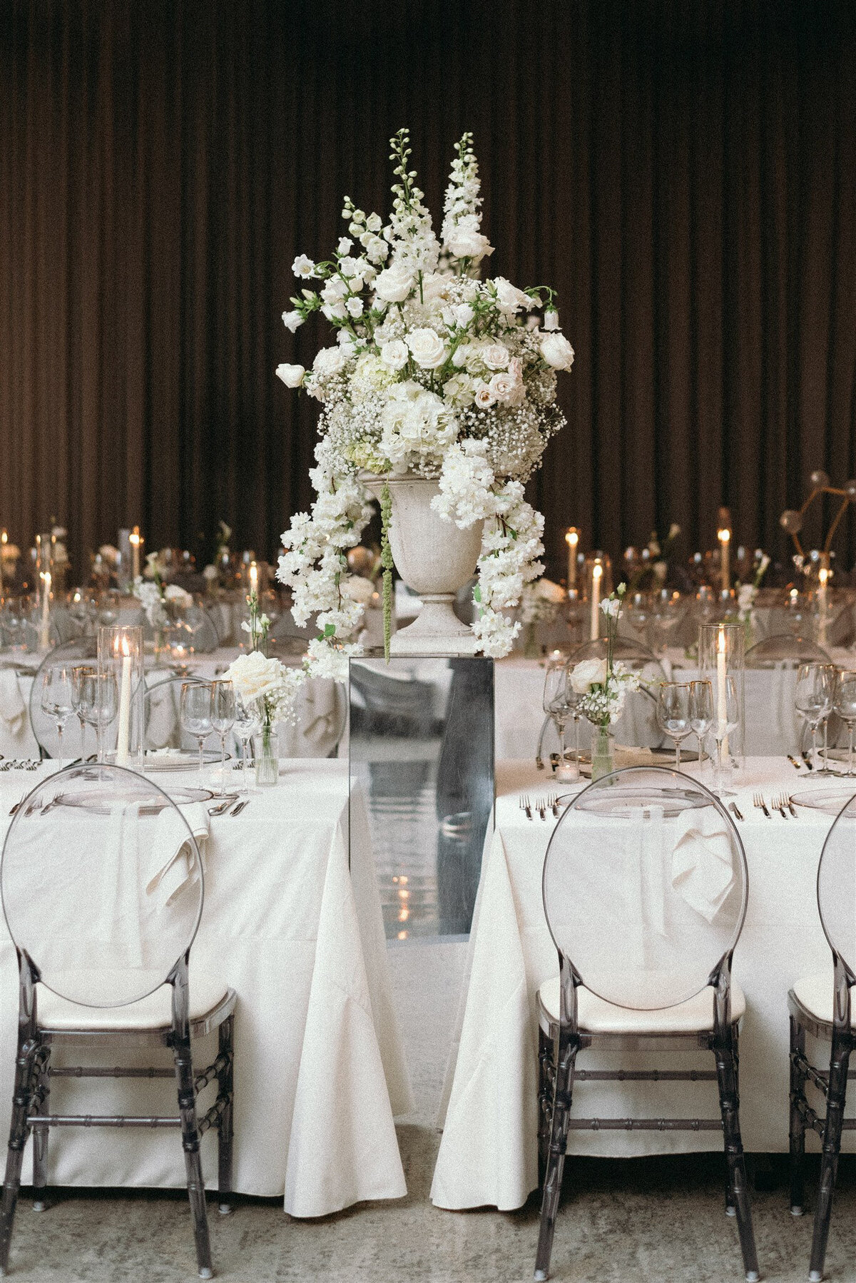 A large urn of elegant white flowers forms a centrepiece between tables at Westbury Ballroom.