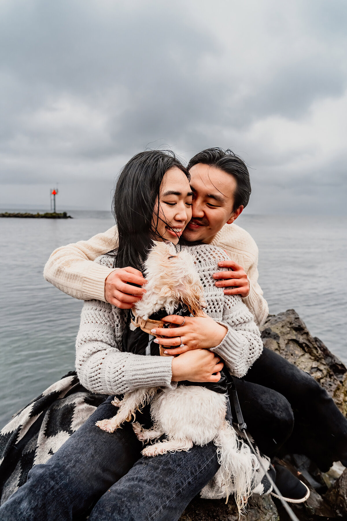 an Asian couple on a Seattle pier embracing in a hug, smiling