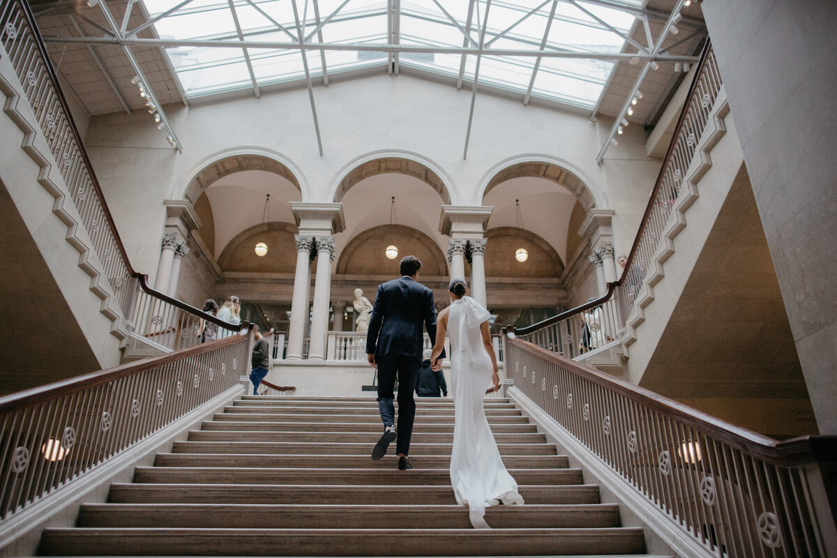Wedding couple walks up steps inside the Art Institute of Chicago