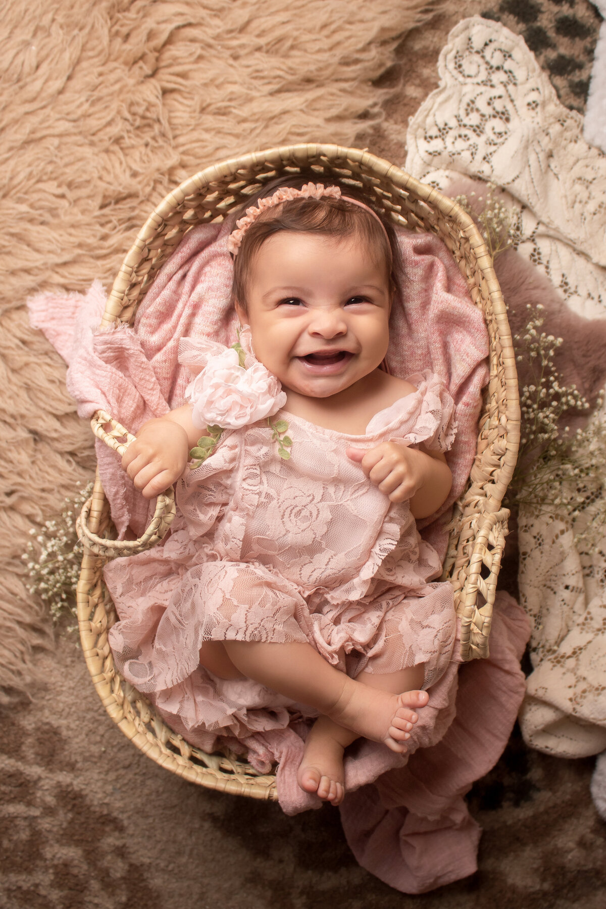 baby girl smiling for the camera while wearing a pink lace outfit during her milestone session