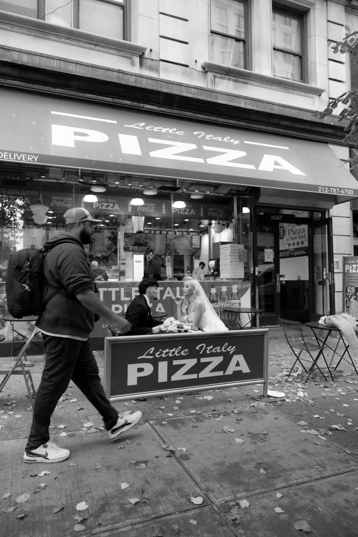 A candid moment of the couple chatting and eating pizza inside a busy NYC pizza shop.