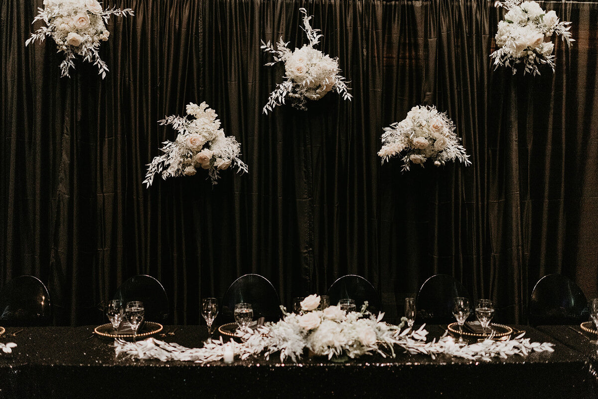 Black decor with white floral accents at wedding party table.