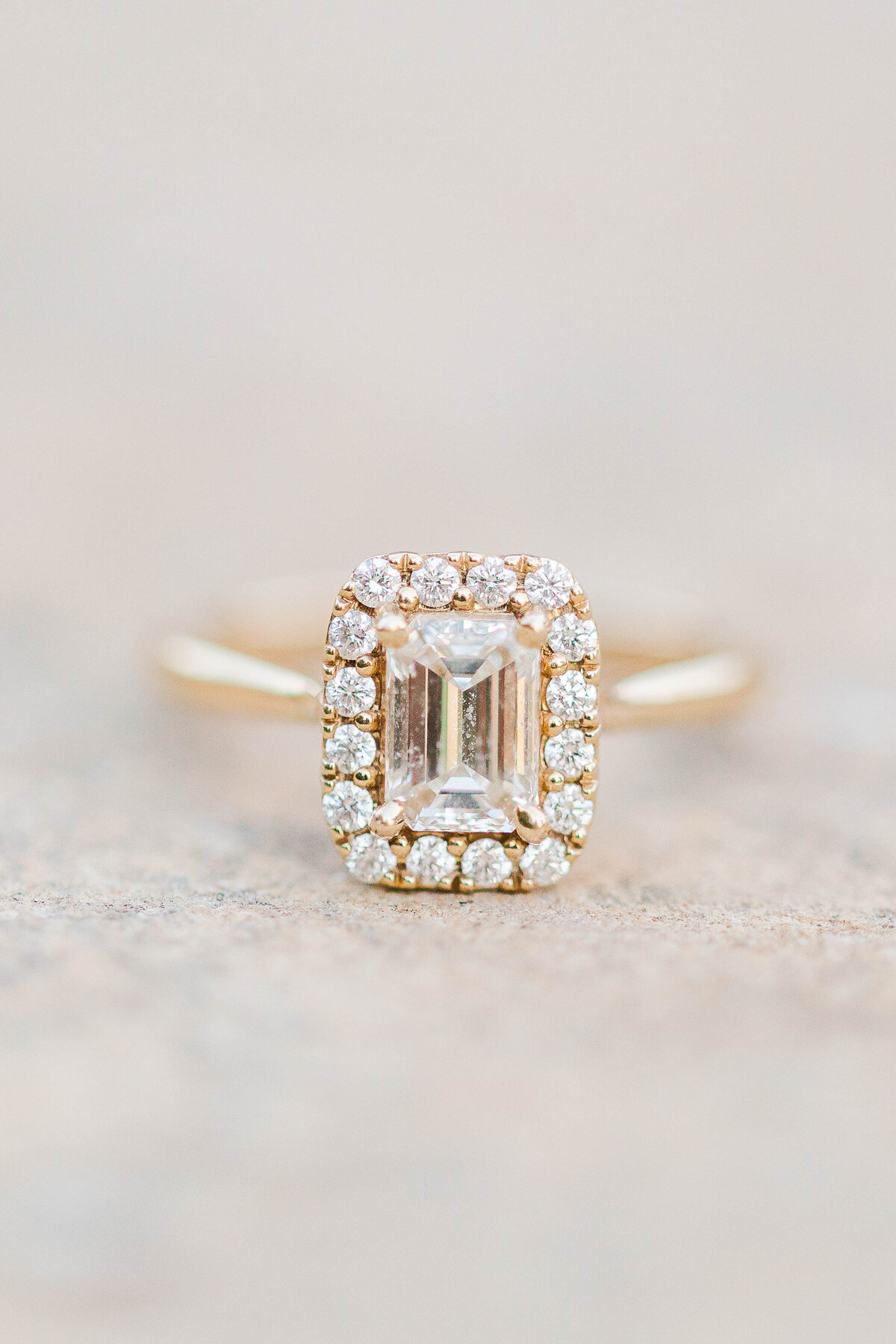 gold-emerald-cut-engagement-ring-surrounded-by-smaller-diamonds