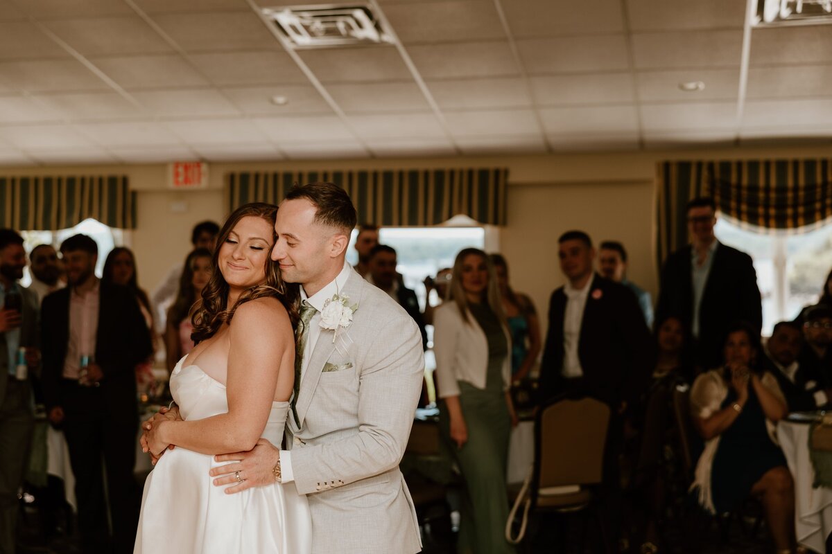 Bride and groom share an emotional first dance during their Westchester wedding reception, surrounded by smiling guests in a warmly lit venue.
