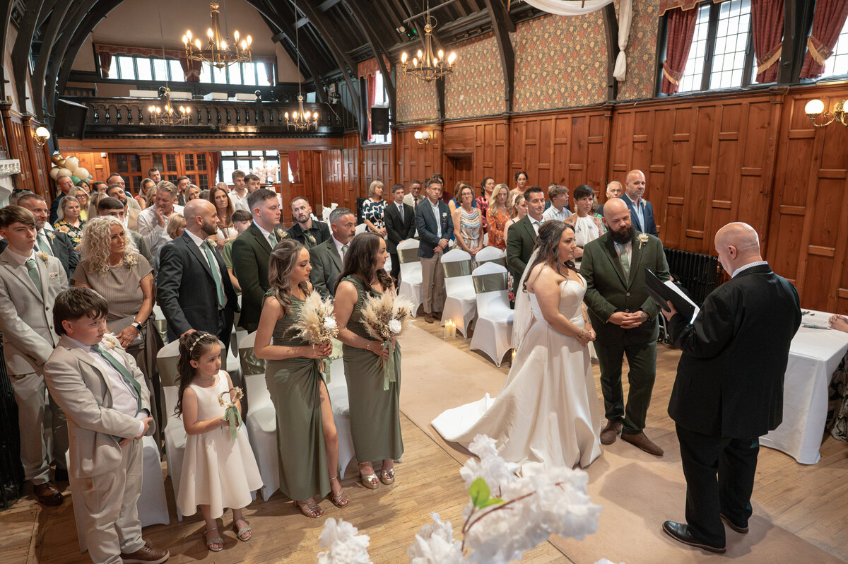 Bride and groom exchanging vows with all guests in photo in Worsley Court House ceremony room.