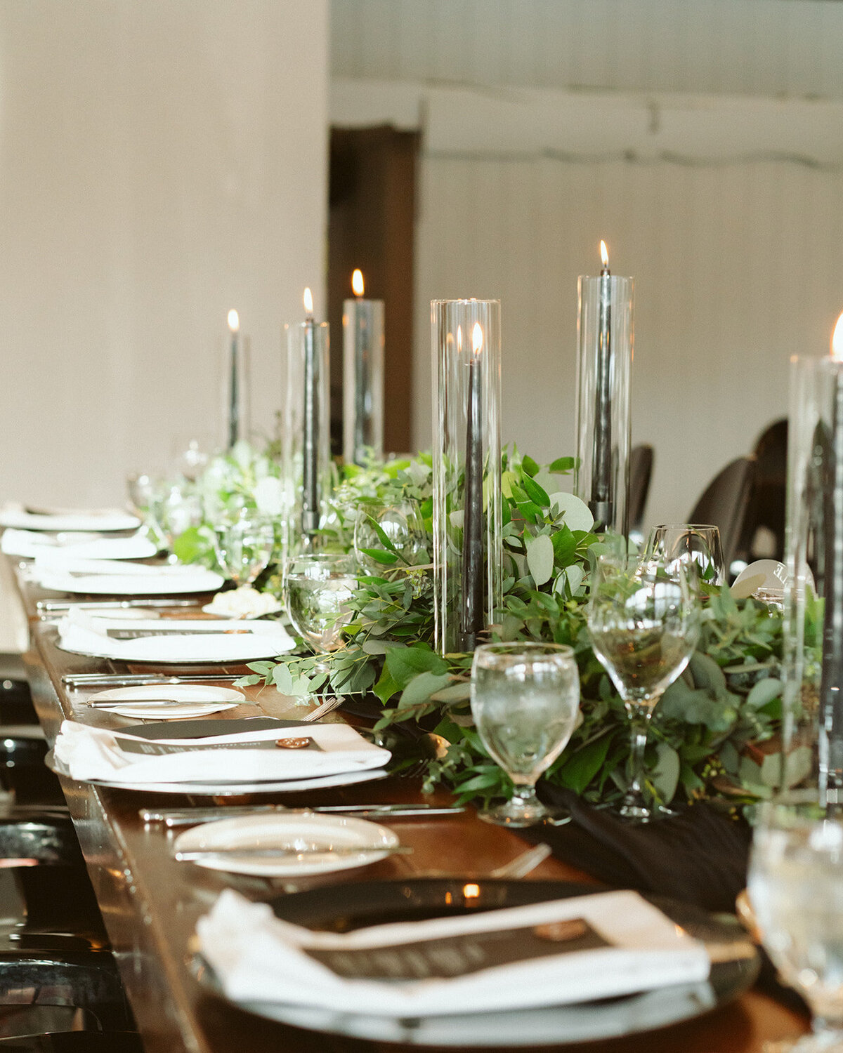Black pillar candles with greenery for winter wedding.