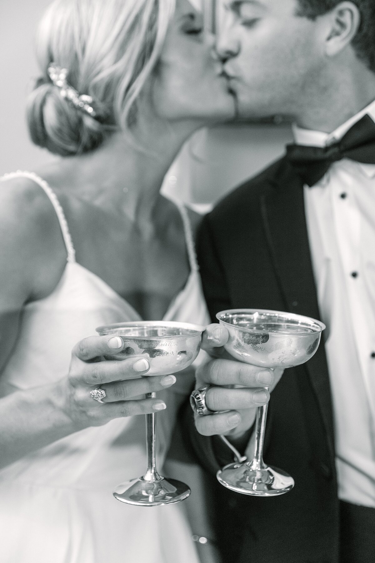 bride + groom kiss while clinking silver coupe glasses