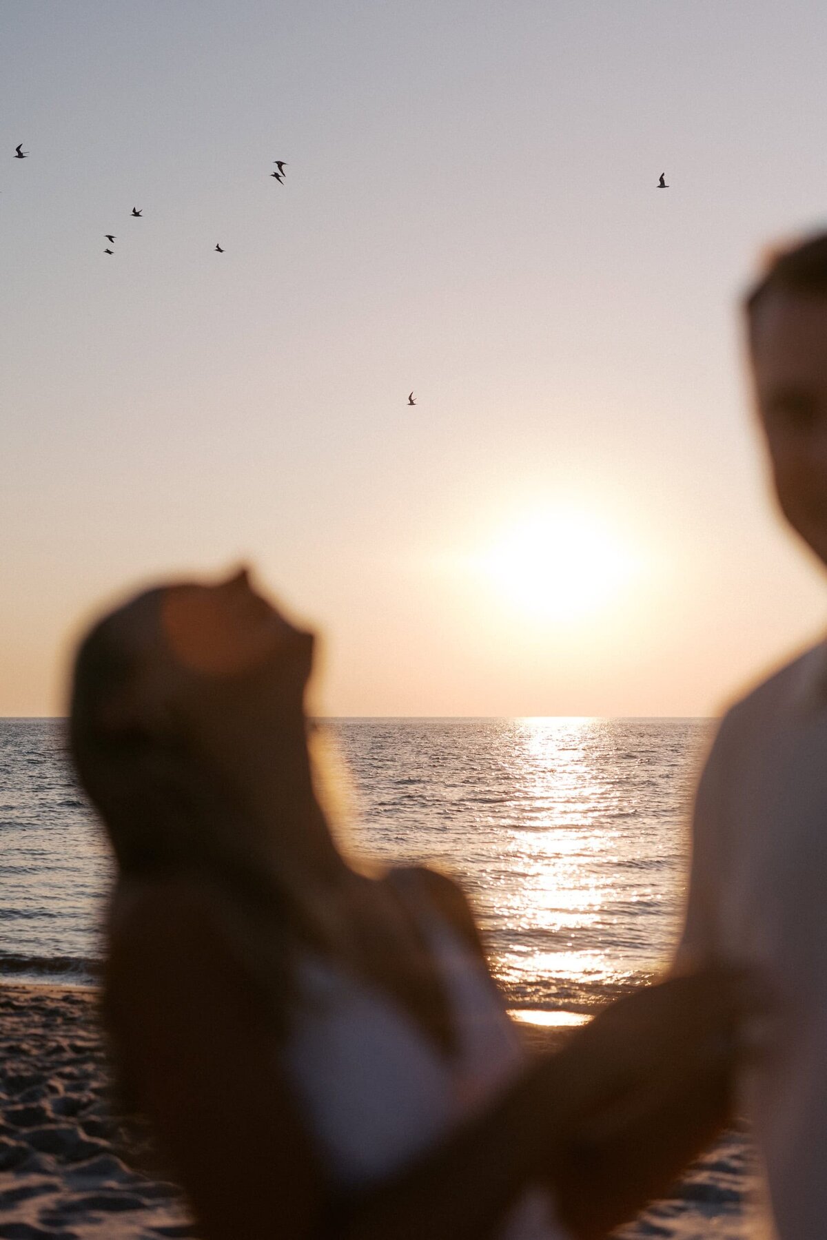 couple looking at birds flying at sunset in cape may nj