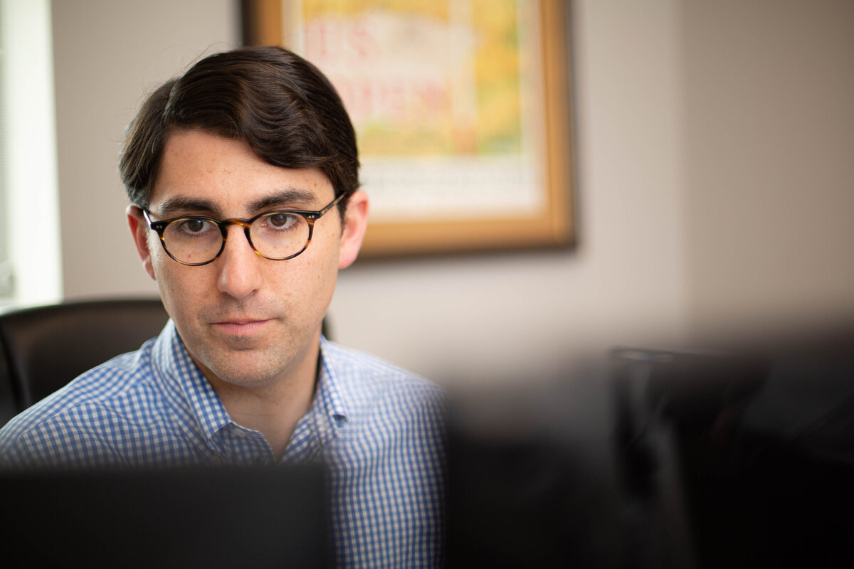 Young caucasian male with glasses looking intently at a computer screen