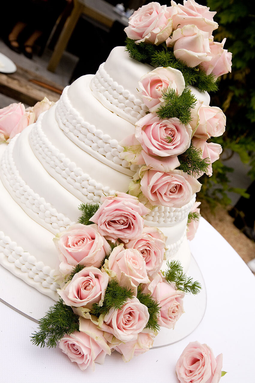 Bruidstaart van Berg's Bakery met verse roze rozen.