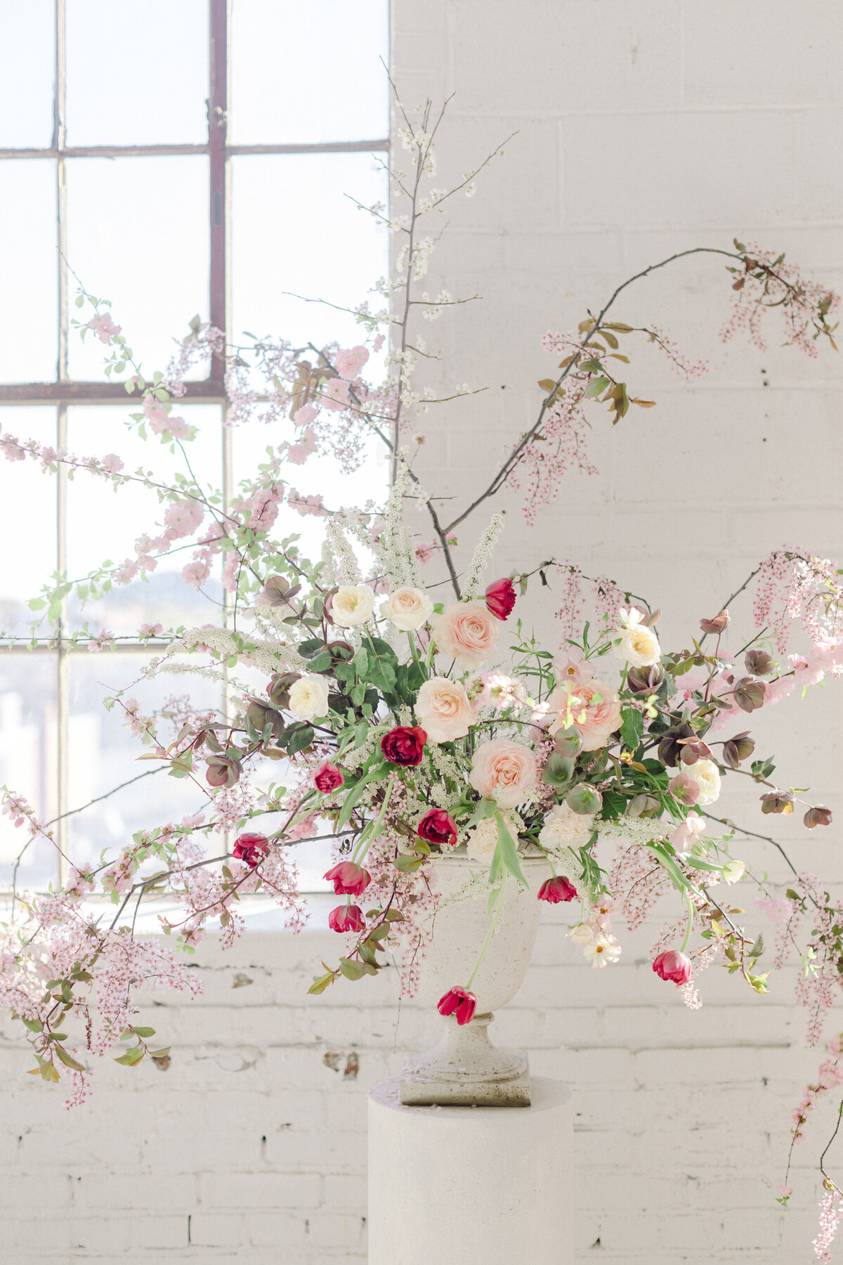 A large, airy, arrangement of pink and white flowers decorates a wedding ceremony at L'Eloi.