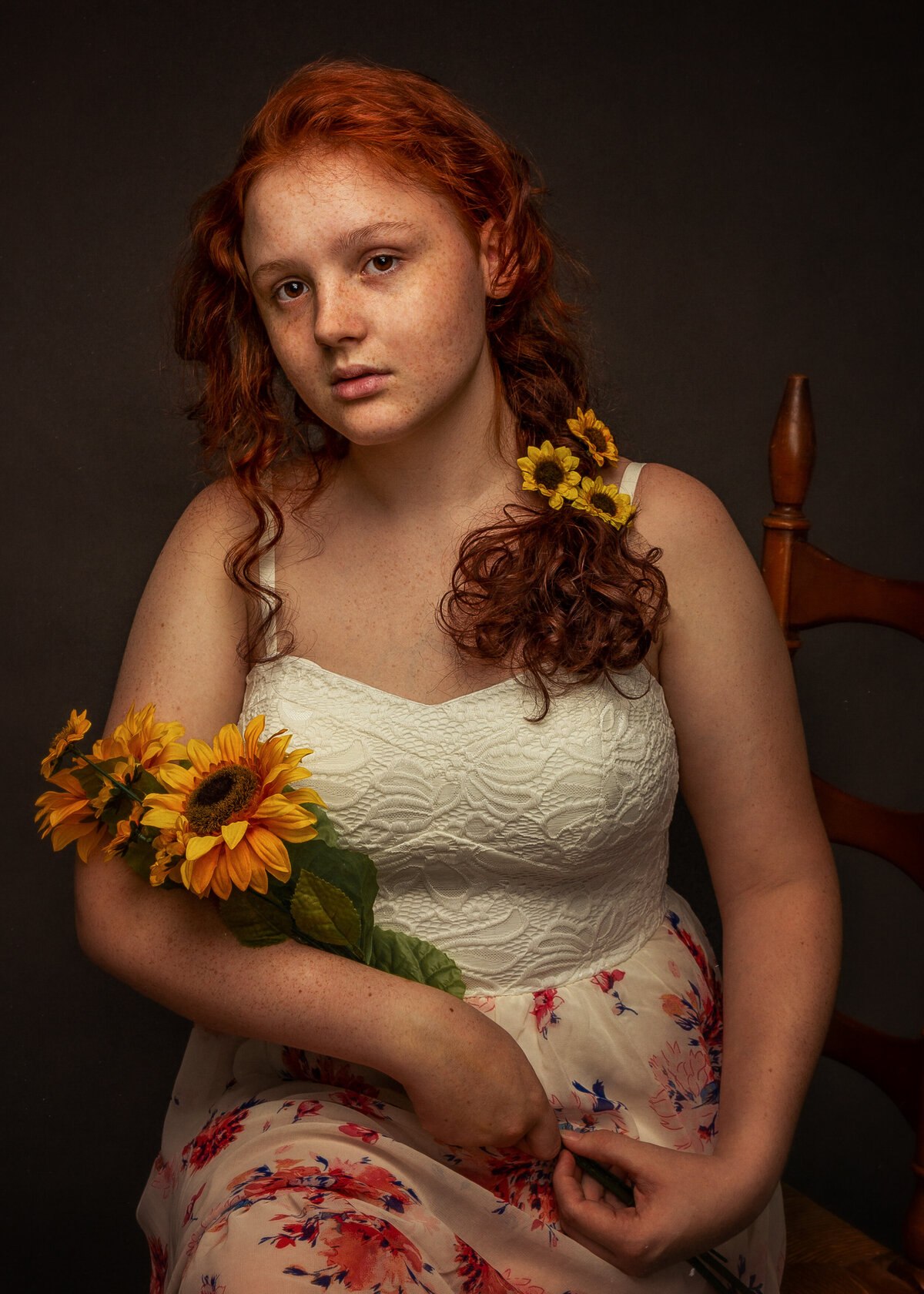 girl in flowery dress holding orange flowers in a studio
