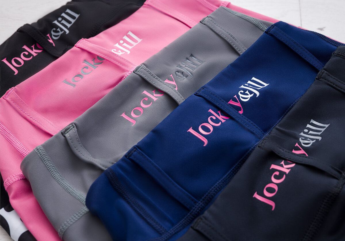 Product shots for Jockey&Jill. Taken in studio by photographer Claire Howes, Norwich. The image is a of various coloured jodhpurs arranged on a flat lay white wooden floor.