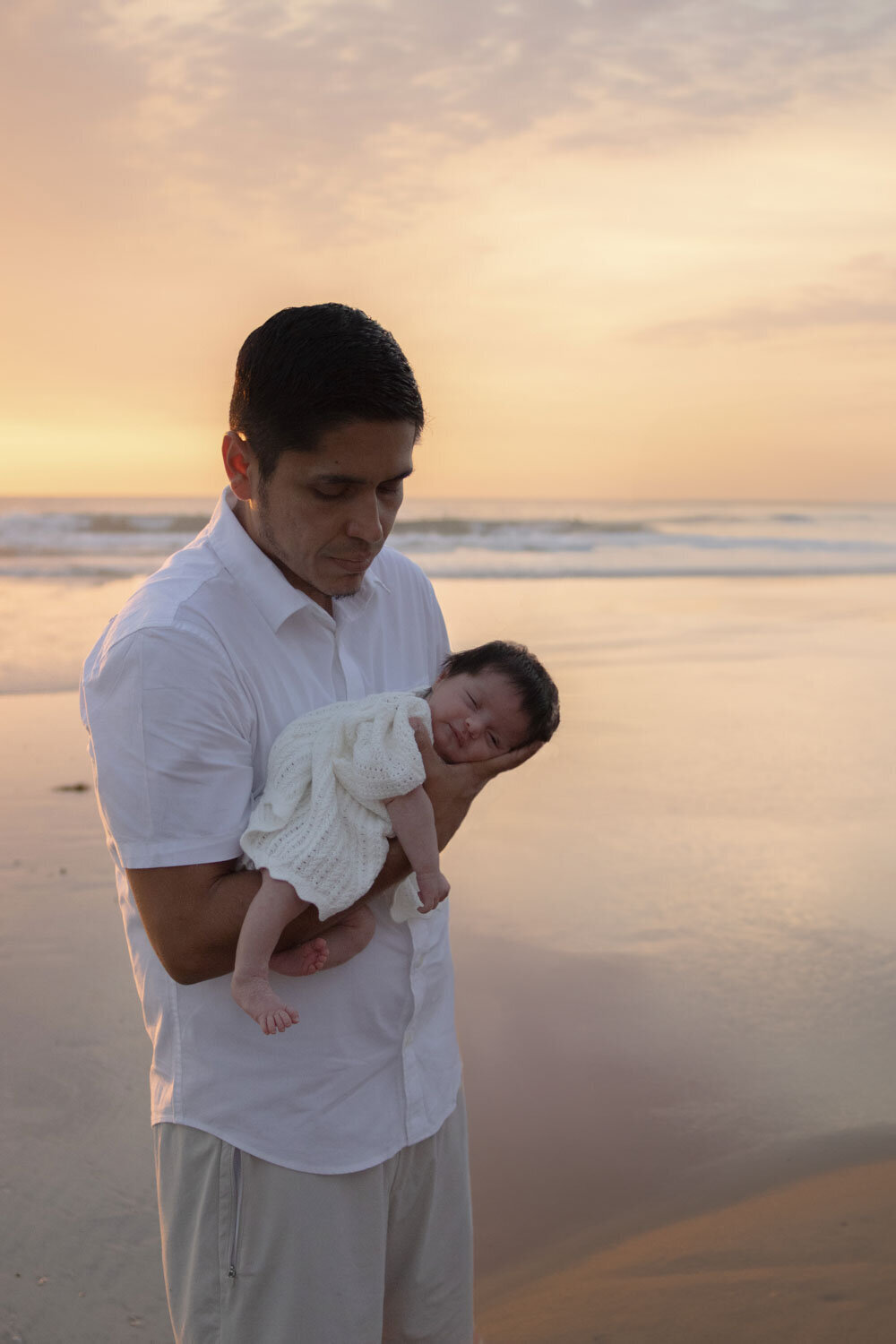 A father holding his newborn while standing at the water's edge