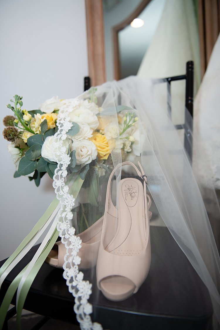 Blush peep-toe heels, veils and wedding bouquet on chair in front of antique mirror