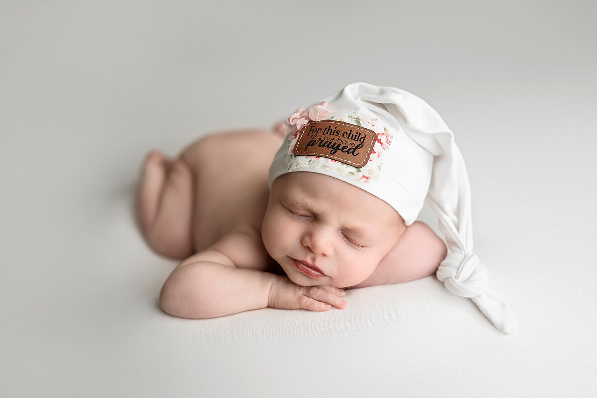 Baby girl posed on white during her newborn photo session.