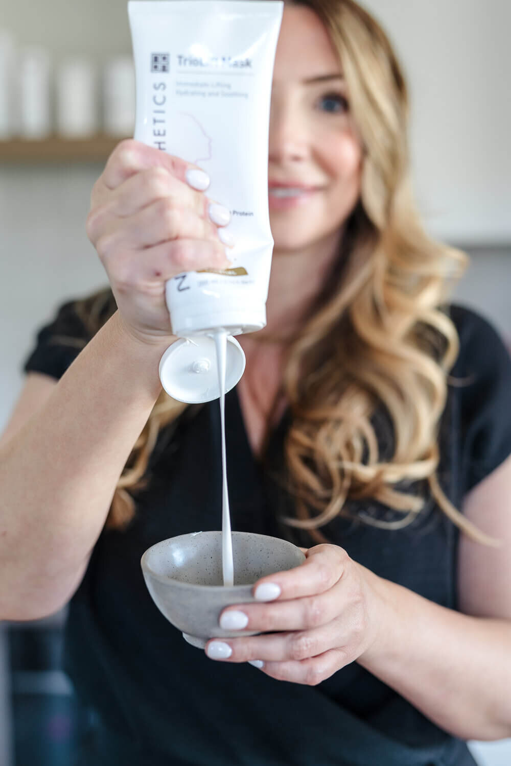 Kelowna spa owner pouring facial cream into small grey bowl