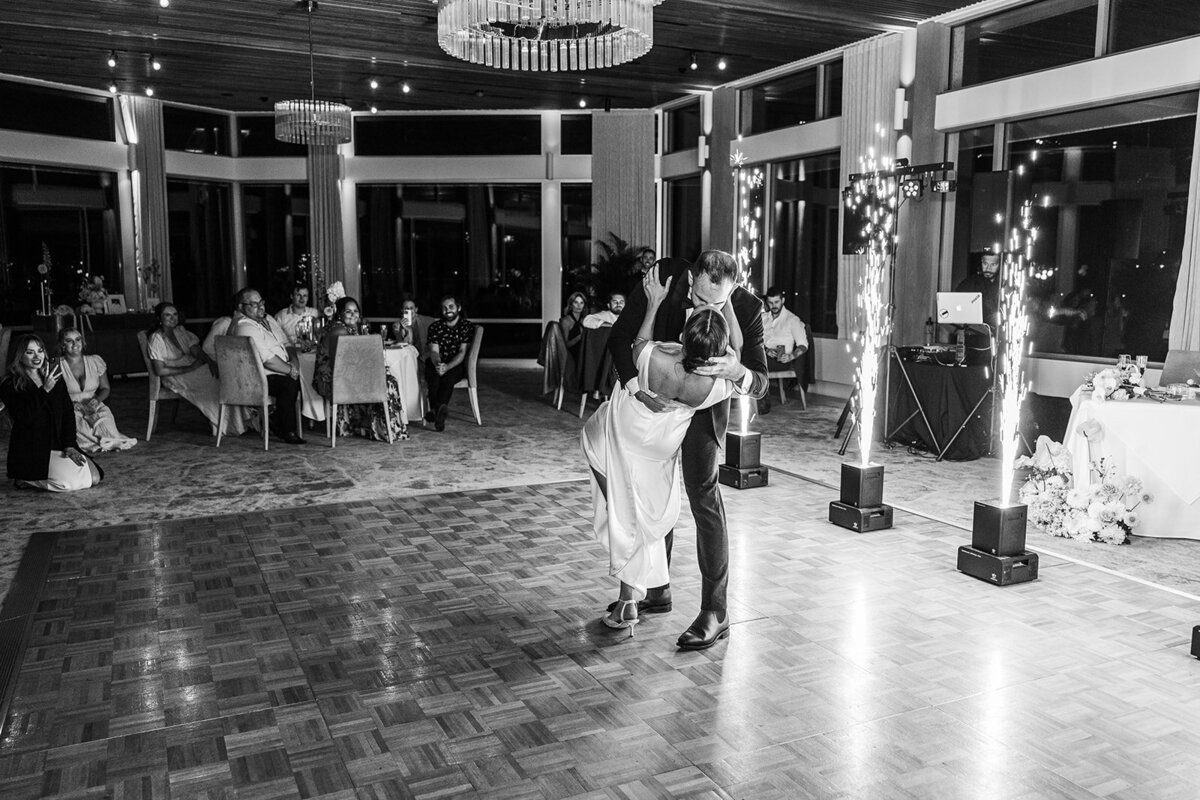 Black and white photo of bride and groom doing a dip during their first dance with fireworks in the background. Image taken at The Marion by Canberra wedding photographer, Acacia & Grace photography.