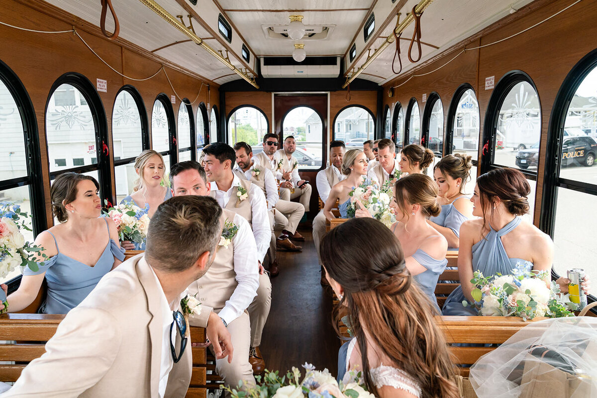 A group of bridesmaids and groomsmen enjoying a ride in a wooden trolley