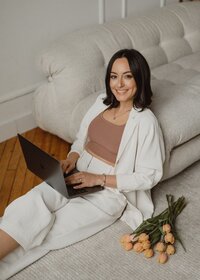 fallback shared on Invalid Date | Vickie from VERVE & COLOR leaning on a cozy couch with a laptop, representing a Showit d...