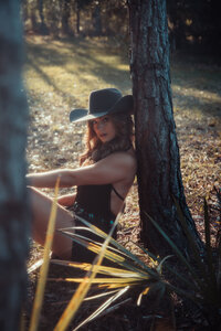 fallback shared on Invalid Date | Woman wearing a black cowboy hat and short black dress leaning against a tree