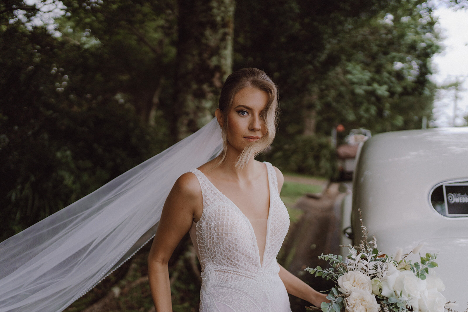 Beautiful Bella Rae  bride Heather Looking gorgeous with soft game makeup and with a long vail on a low bun with soft waves framing the  face captured  by Artography Weddings at Tiffanys Maleny