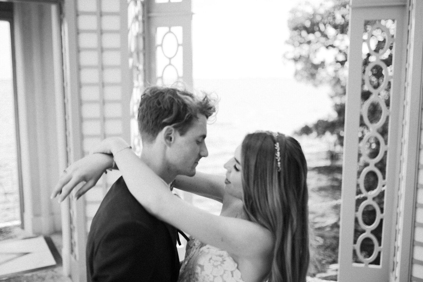 black and white image of bride and groom about to kiss in a waterside viewing tower