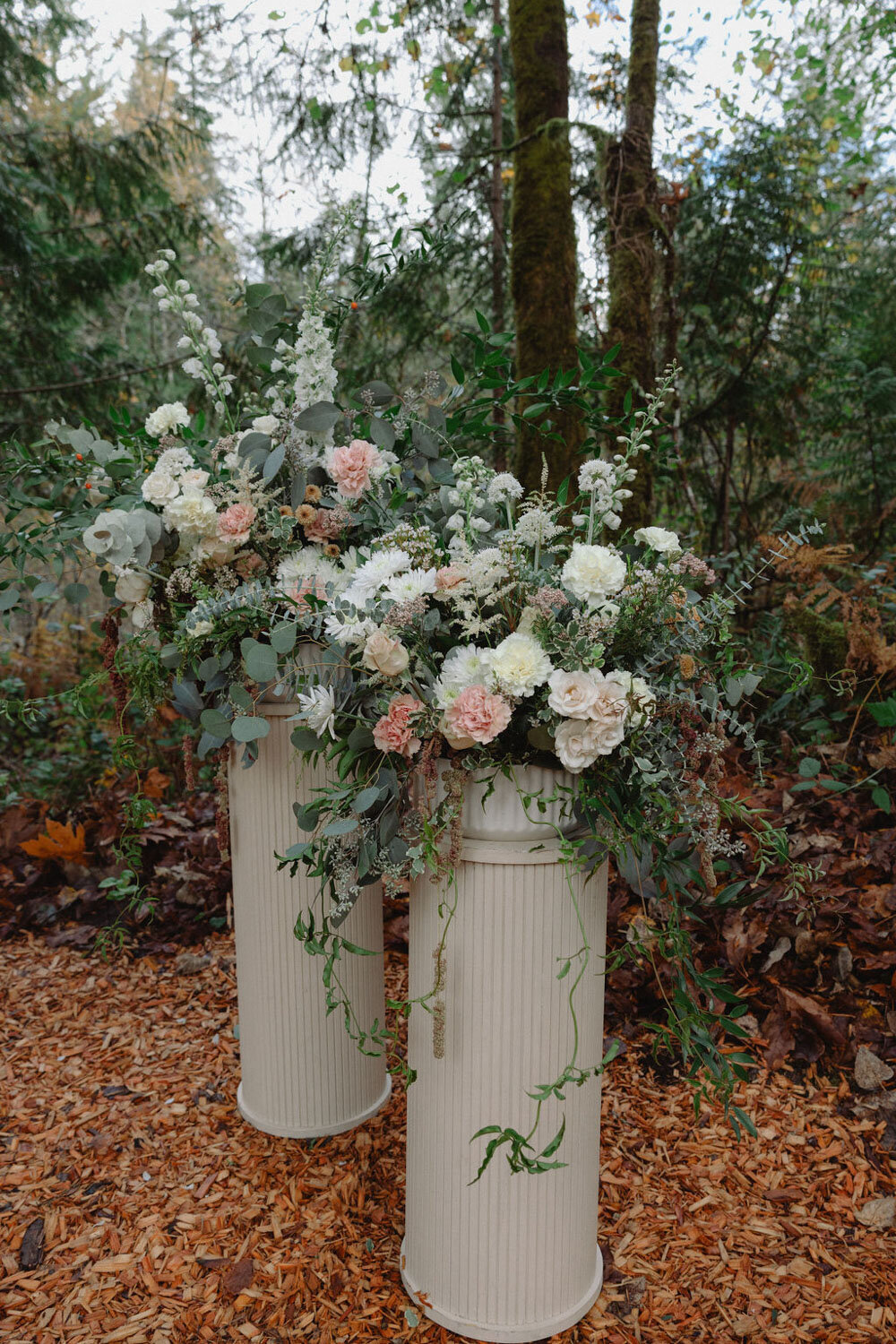 Tall floral arrangements with white and blush flowers on white pillars