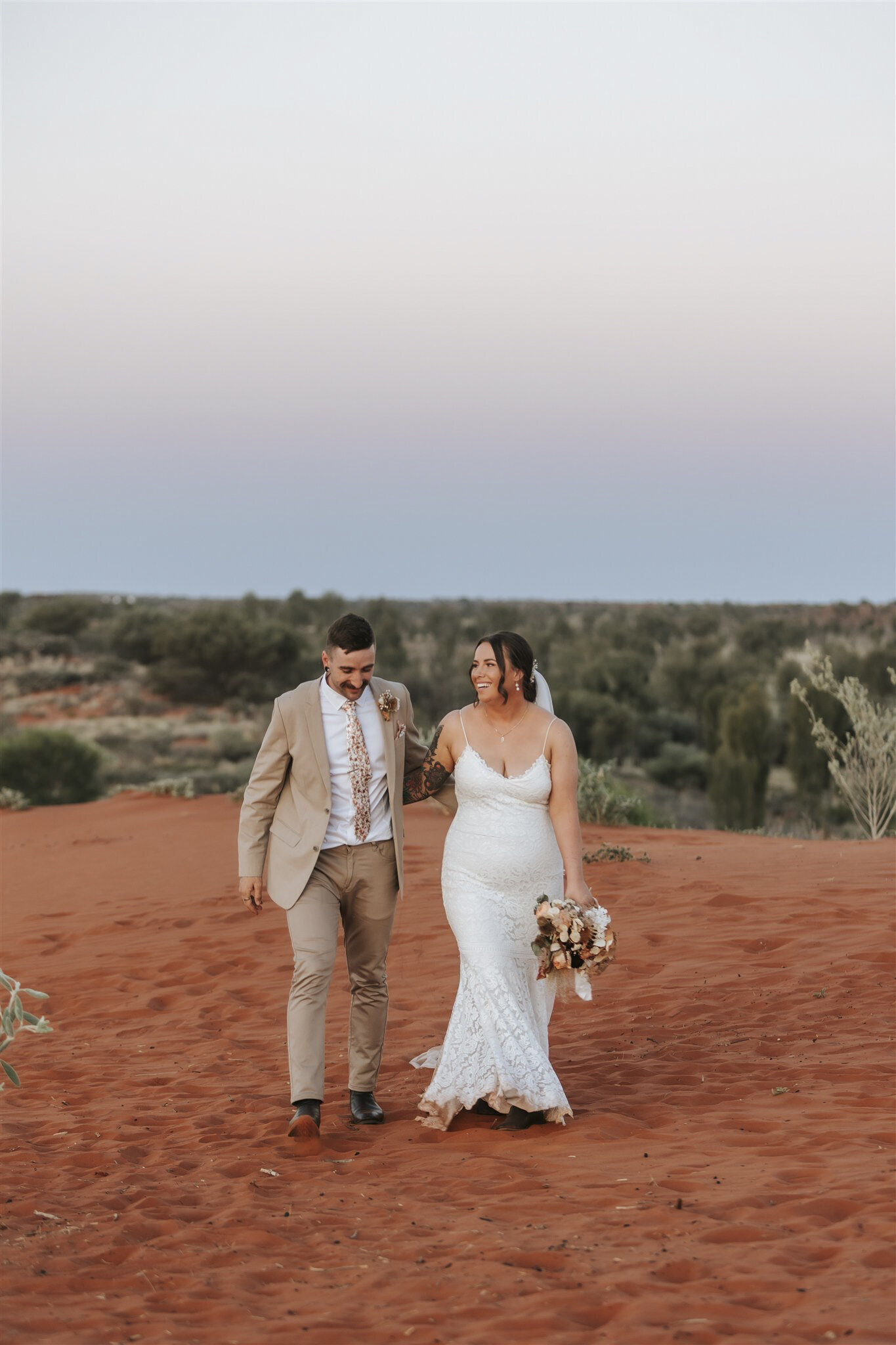 Uluru wedding showing a woman in a wedding dress and a man with a beige suit in the desert